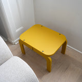 Curry children's table on a wooden floor next to a gray sofa.