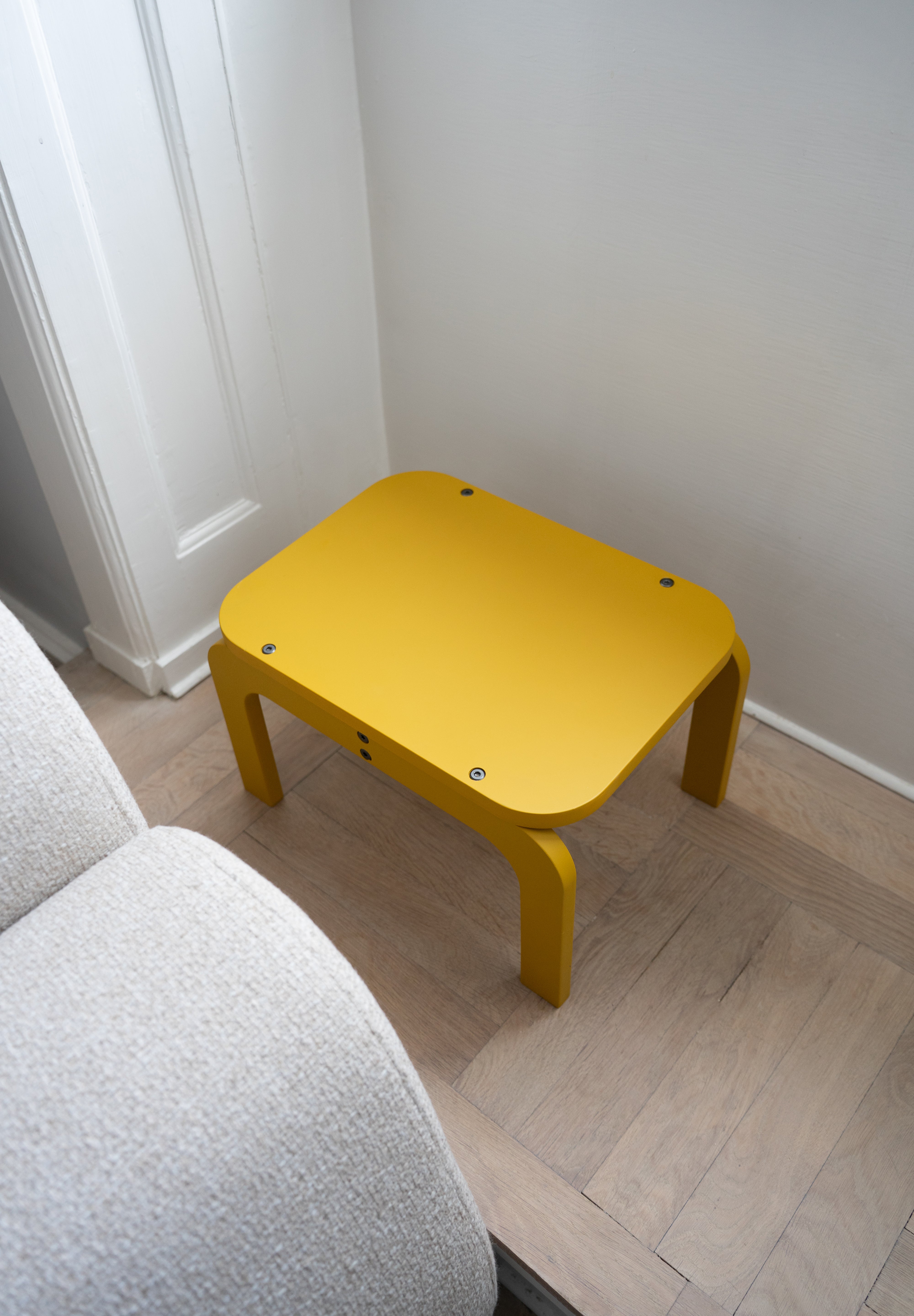 Curry children's table on a wooden floor next to a gray sofa.
