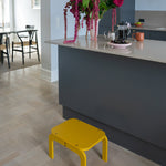 Curry step stool in a modern kitchen with a gray island and floral arrangement.