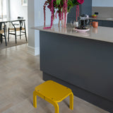 Curry step stool in a modern kitchen with a gray island and floral arrangement.