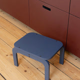 Blue stool on a wooden floor with red cabinets in the background