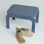 Blue stool with a single rain boot on a white background