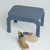 Blue stool with a single rain boot on a white background