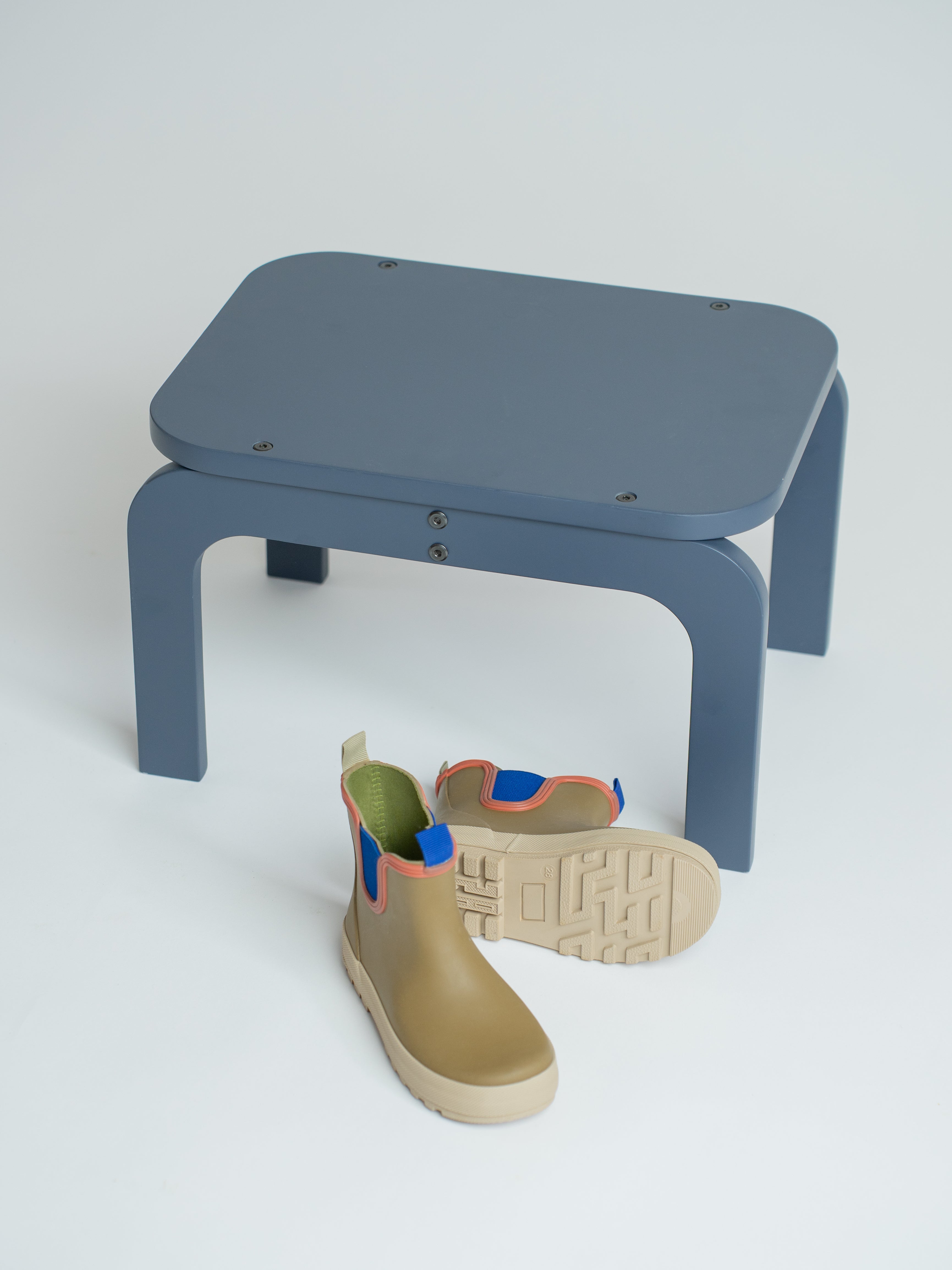 Blue stool with a single rain boot on a white background