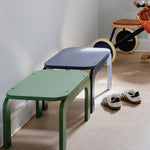 Two children's stools in green and blue on a wooden floor with a bicycle in the background.