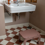 Bathroom with a sink, step stool, and checkered floor.
