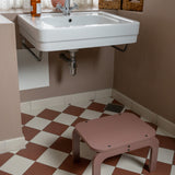 Bathroom with a sink, step stool, and checkered floor.
