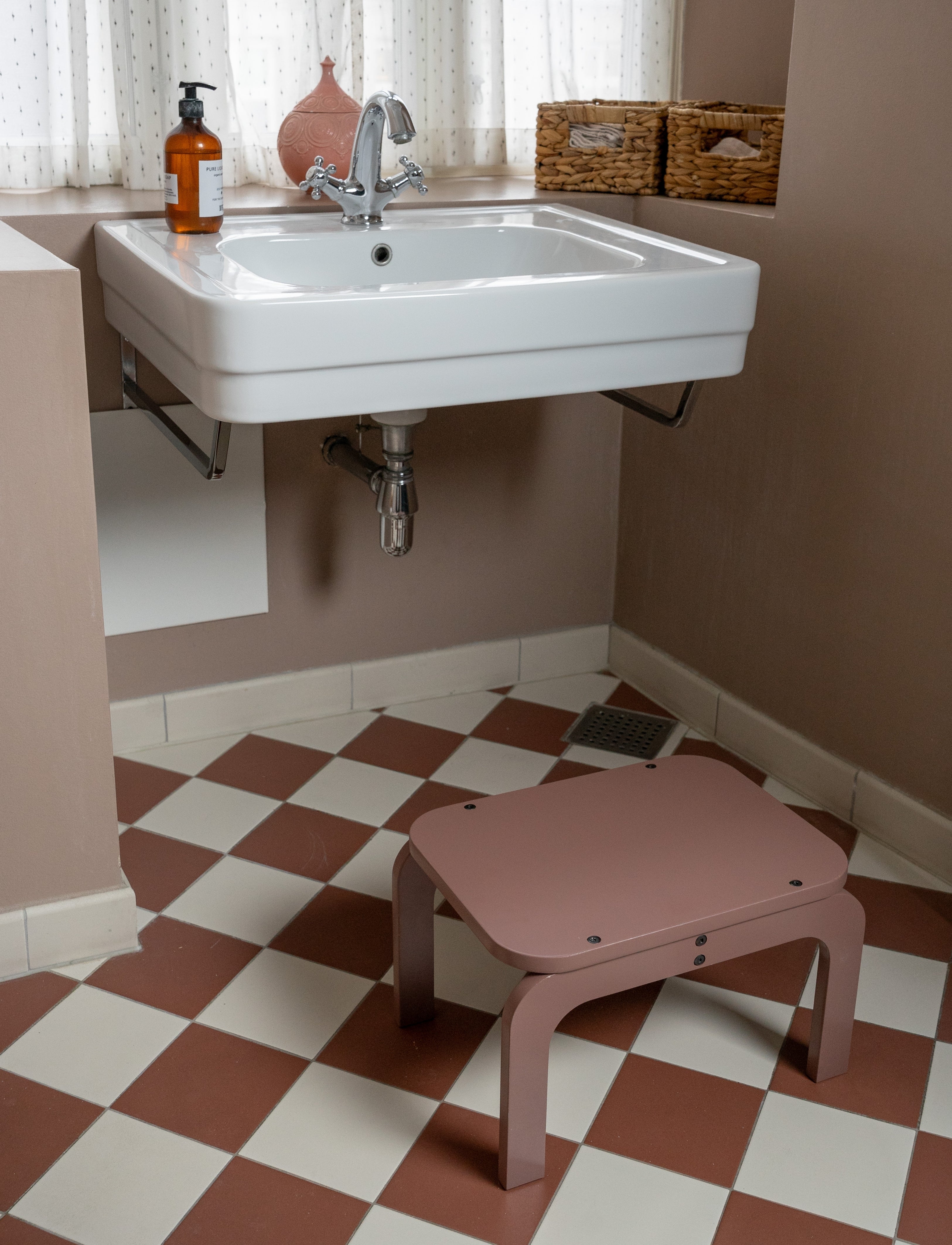 Bathroom with a sink, step stool, and checkered floor.