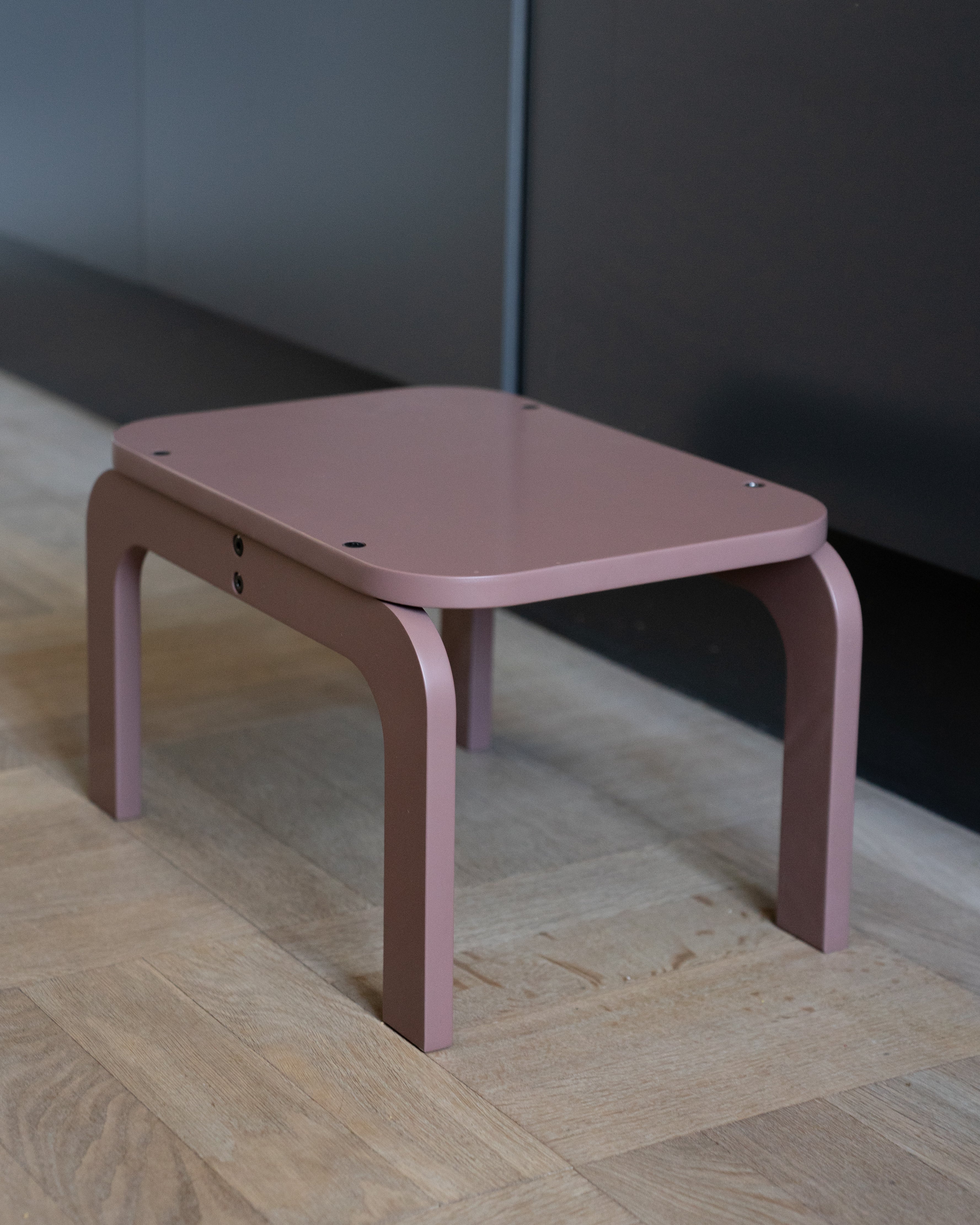 Pink children's table on a wooden floor with a neutral wall background