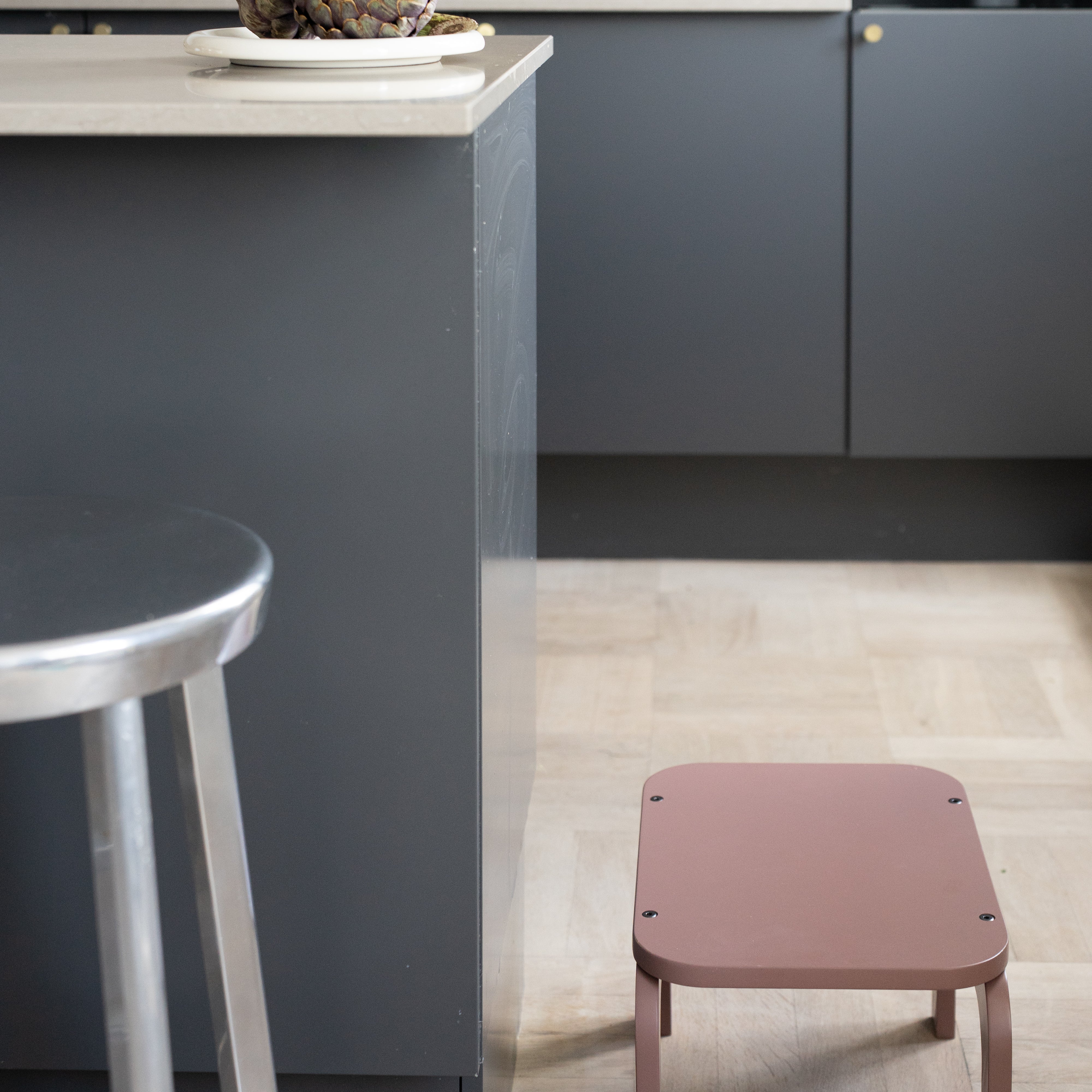 Modern kitchen with a gray island and pink stool
