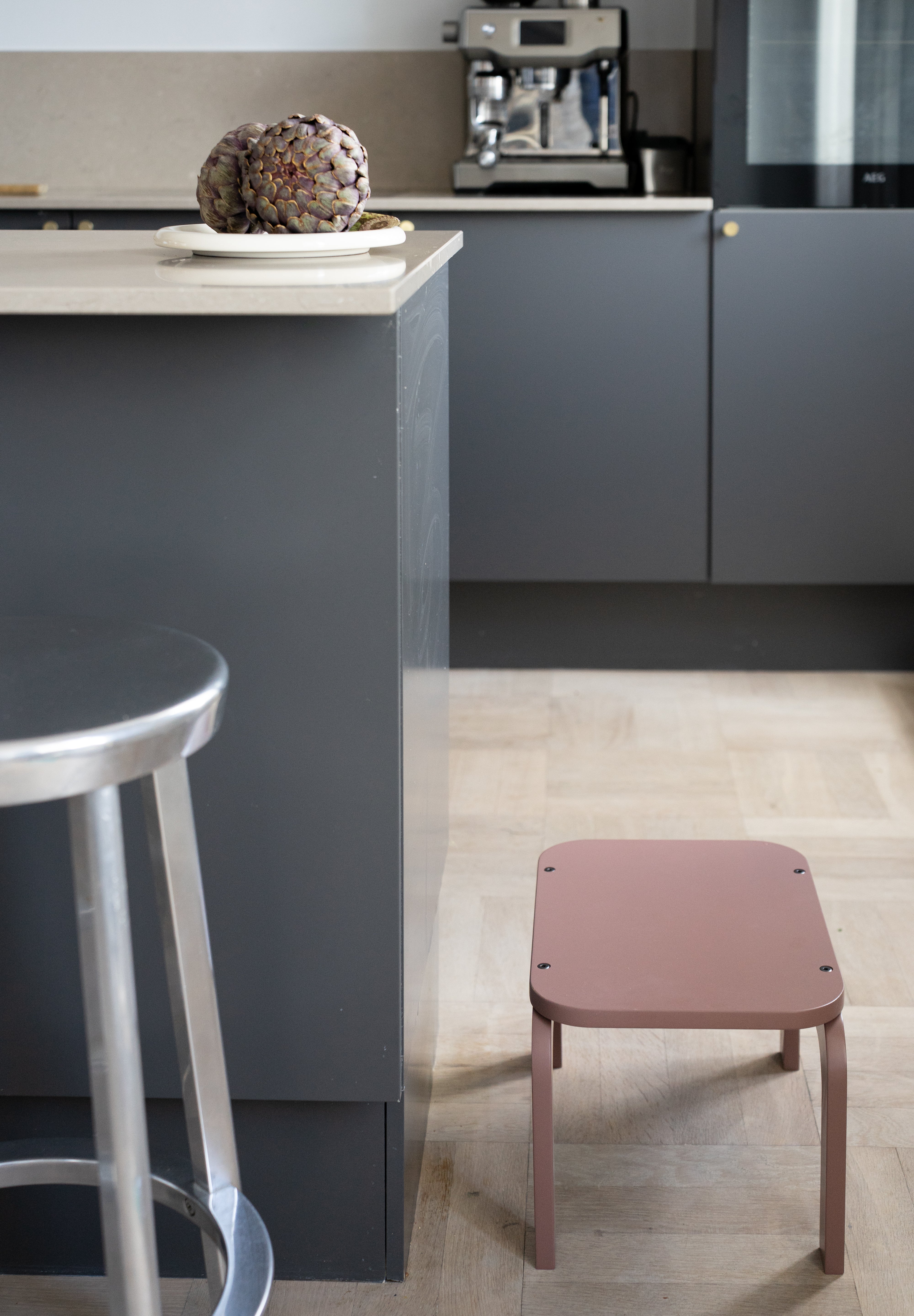 Modern kitchen with a gray island and pink stool