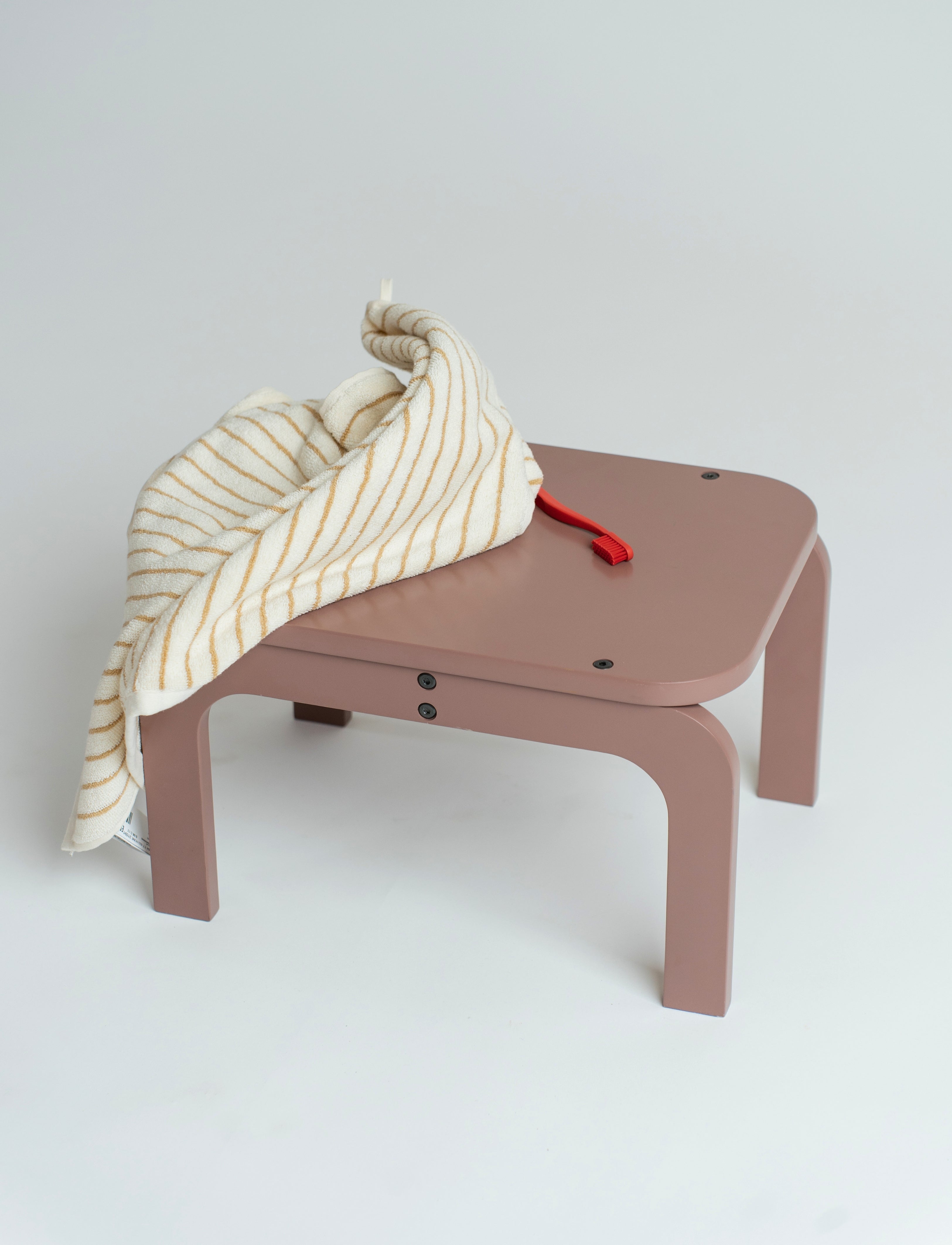 Children's table with a striped cloth and red toy on a light gray background