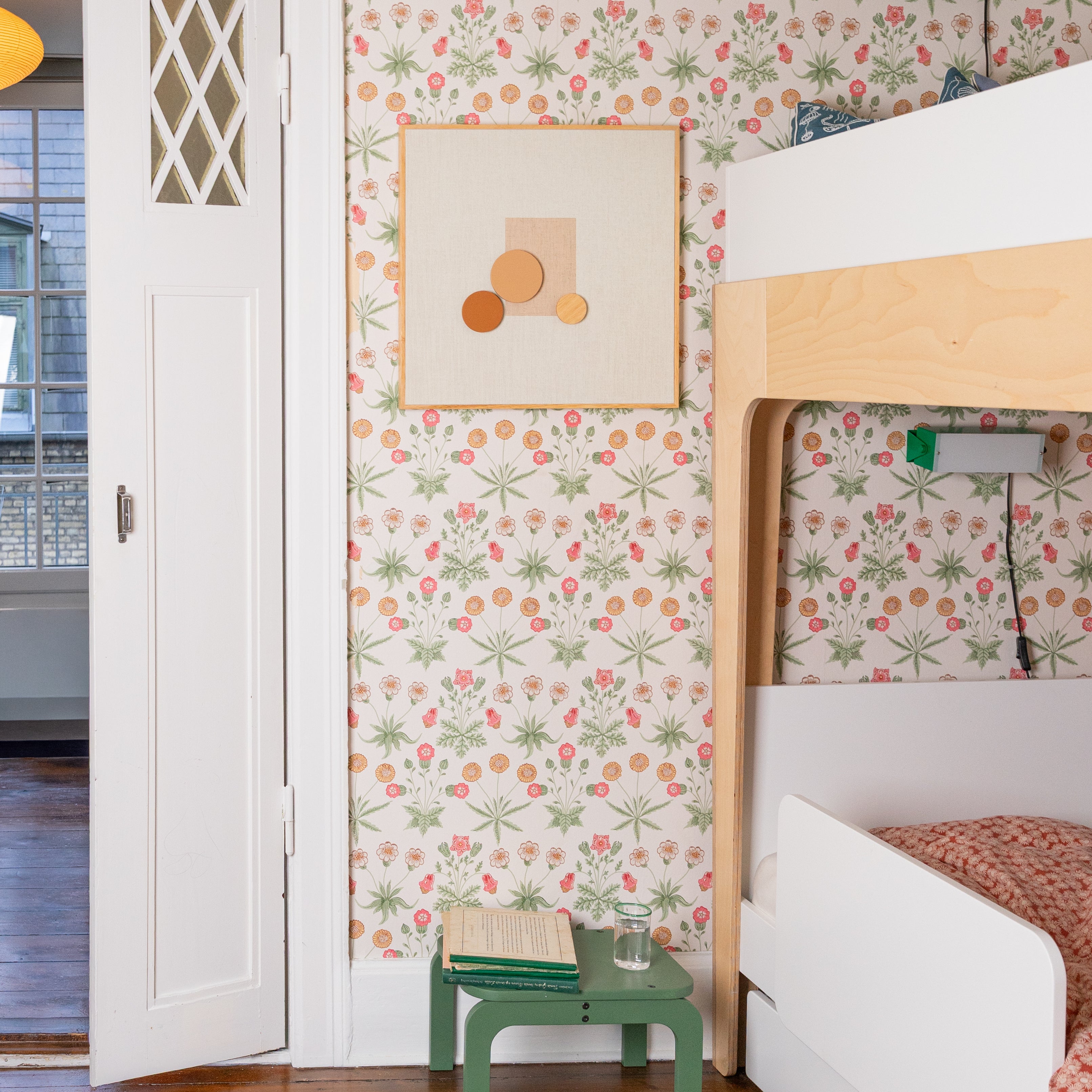 Children's room with floral wallpaper, bunk bed, and green stool.