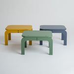 Three colorful stools in yellow, green, and blue on a white background