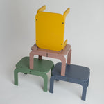 Set of colorful stools in yellow, pink, green, and blue on a light gray background