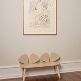 Beige bench with ear design against a wall with a framed picture