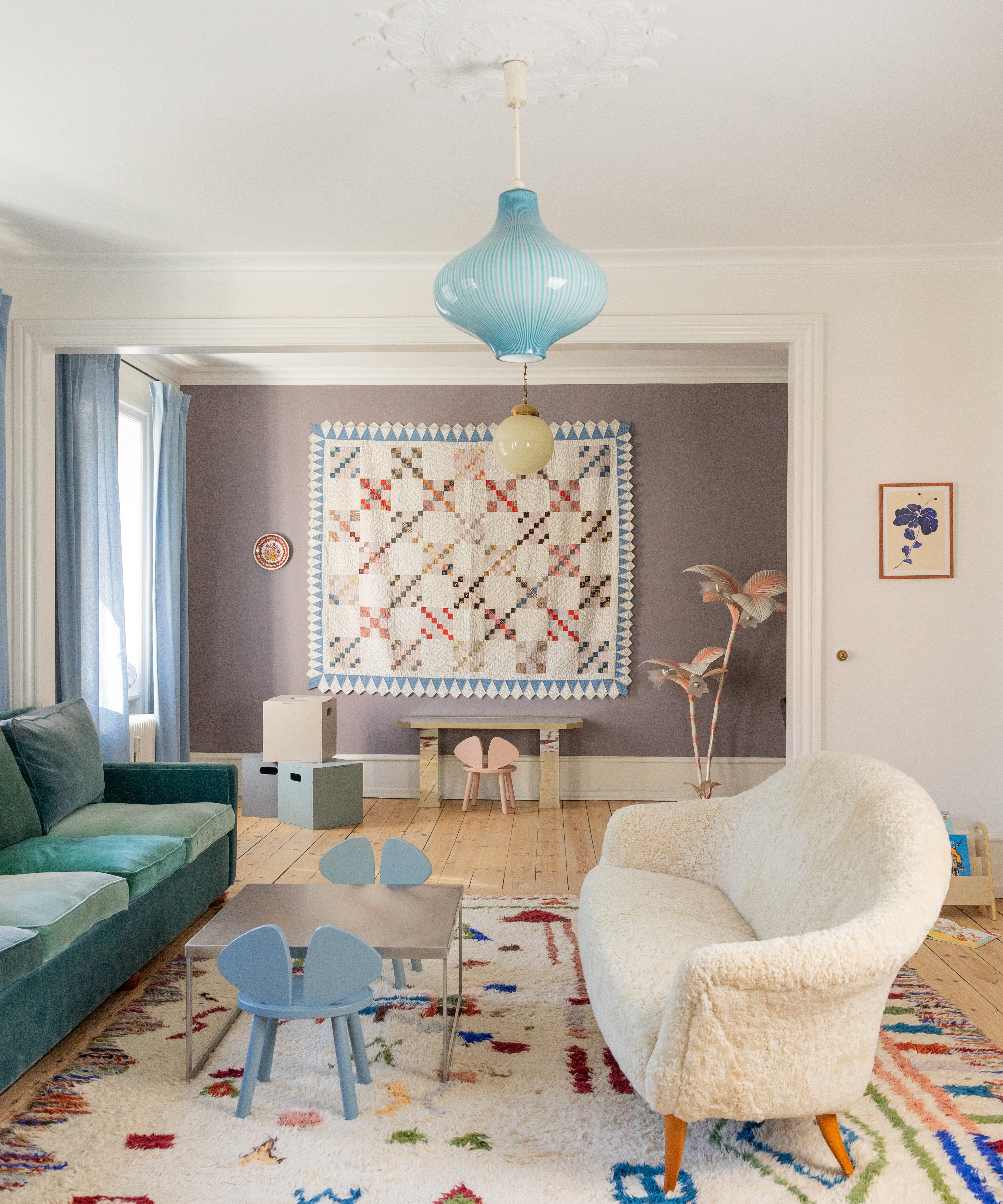 Modern living room with a colorful rug, blue sofa, and white armchair.