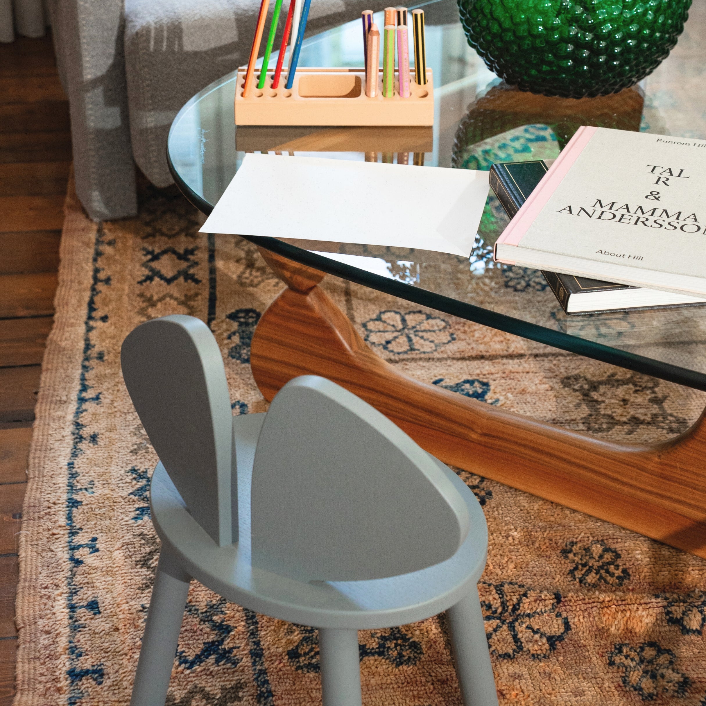  close view of a grey wooden chair standing in the living room next to a glass table