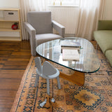 Living room with a glass coffee table, armchair, and small chair on a patterned rug.