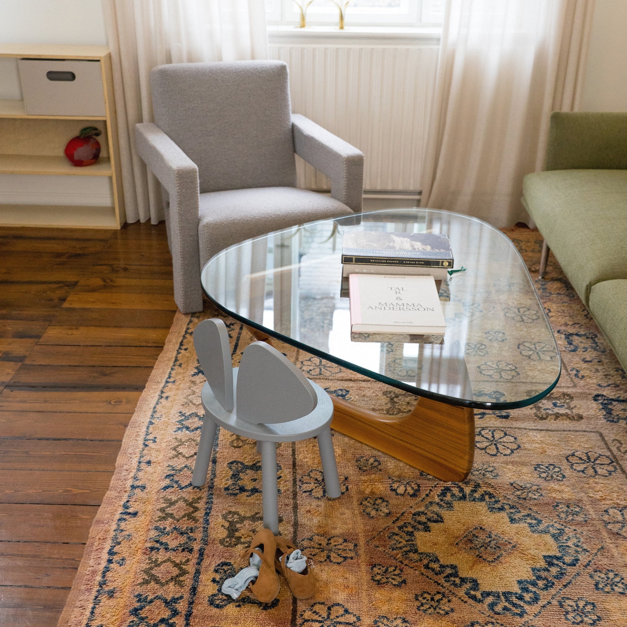 Living room with a glass coffee table, armchair, and small chair on a patterned rug.