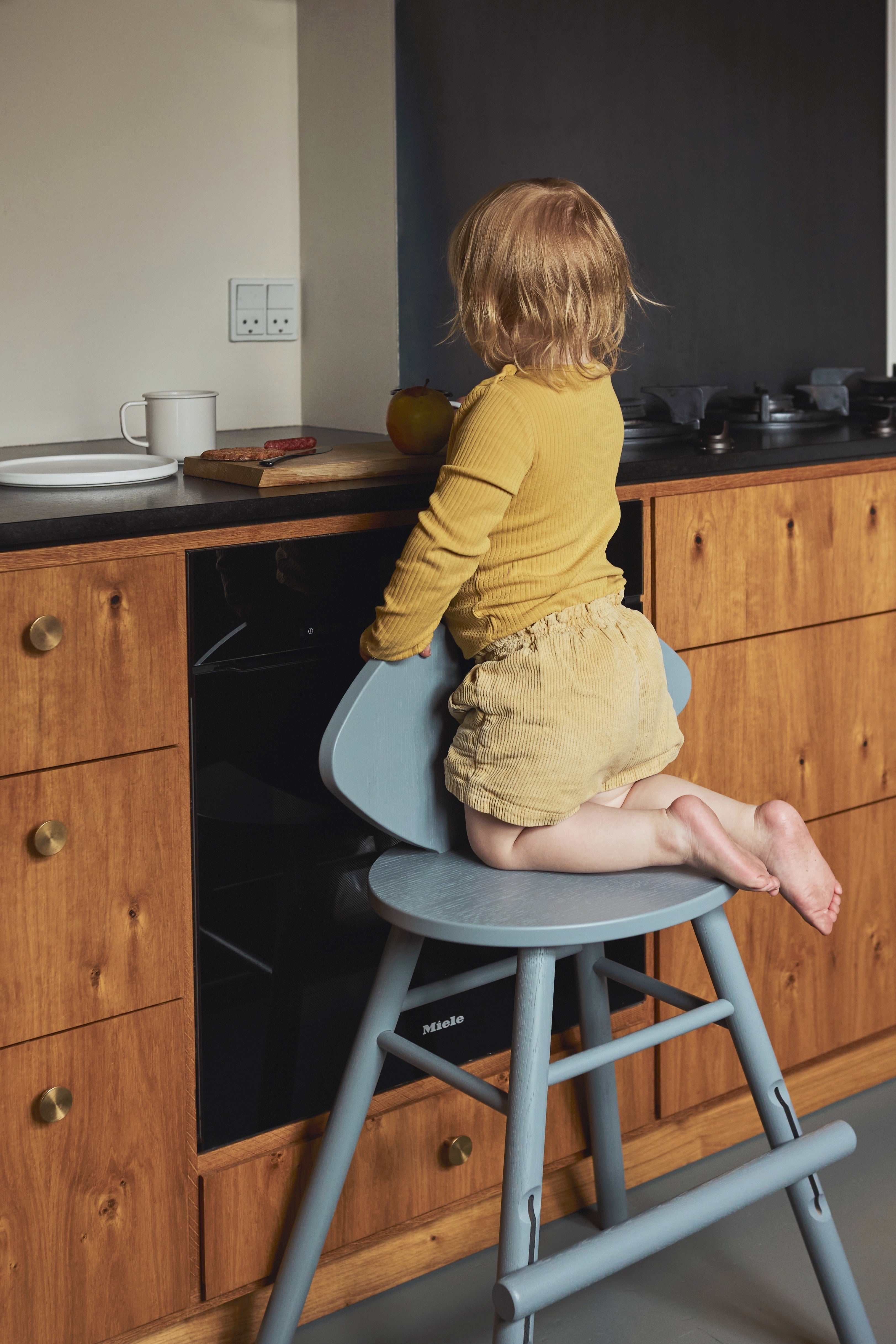 Child sitting on a high chair in a kitchen