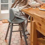 Person sitting at a wooden table with a gray chair on a terracotta tiled floor.