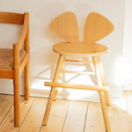 Wooden chair with bunny ears design on a wooden floor.