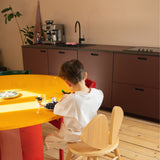 Child sitting at a yellow table in a modern kitchen