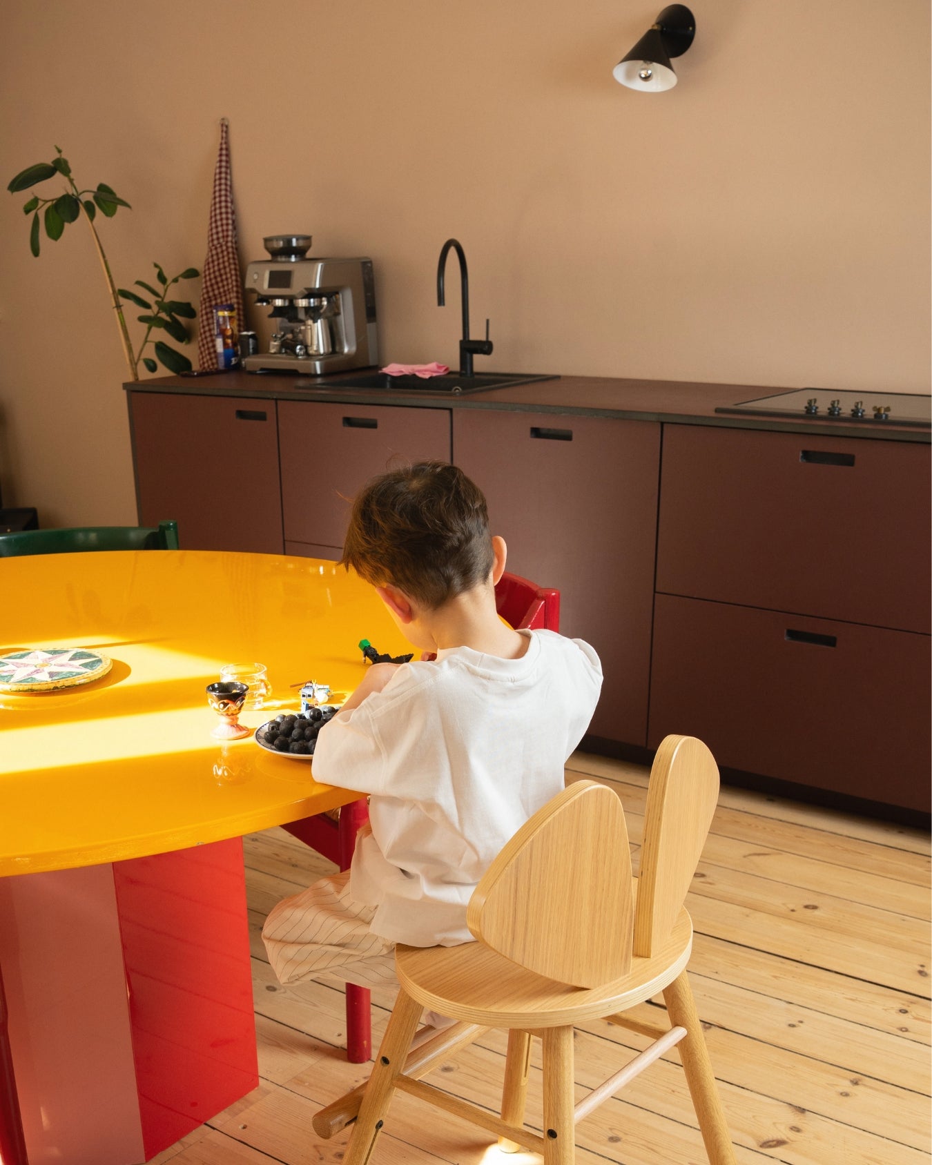 Child sitting at a yellow table in a modern kitchen