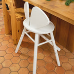 White bar stool in front of a wooden counter on a terracotta tiled floor.