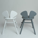 Two modern butterfly-style chairs shown side by side against a light gray studio background. The left chair is white, and the right chair is gray.