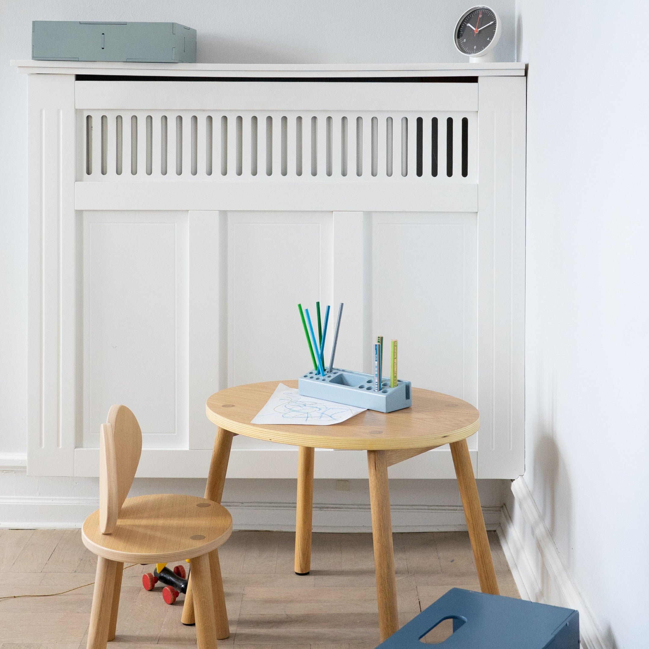 Children's wooden table and chair set with stationery against a white wall.