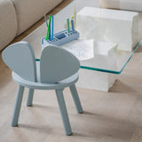 Children's chair with a small table and stationery holder on a light wood floor.