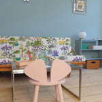 Children's room with a colorful bench, pink chairs, and a small table.