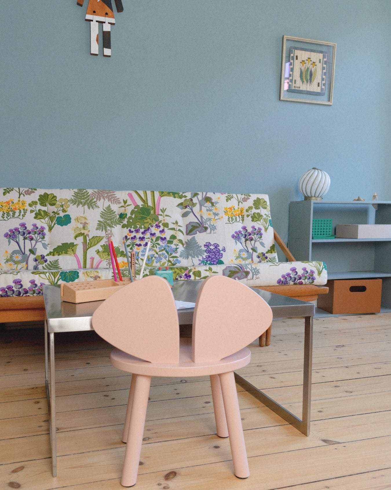 Children's room with a colorful bench, pink chairs, and a small table.
