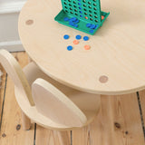 Children's wooden table and chair set with colorful game pieces on a wooden floor.