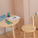 Children's wooden table and chair set with art supplies on a wooden floor.