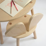 Wooden children's table and chair set with notebooks and pencils on a white background