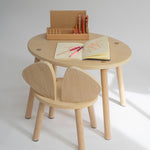 Wooden children's table and chair set with art supplies on a white background