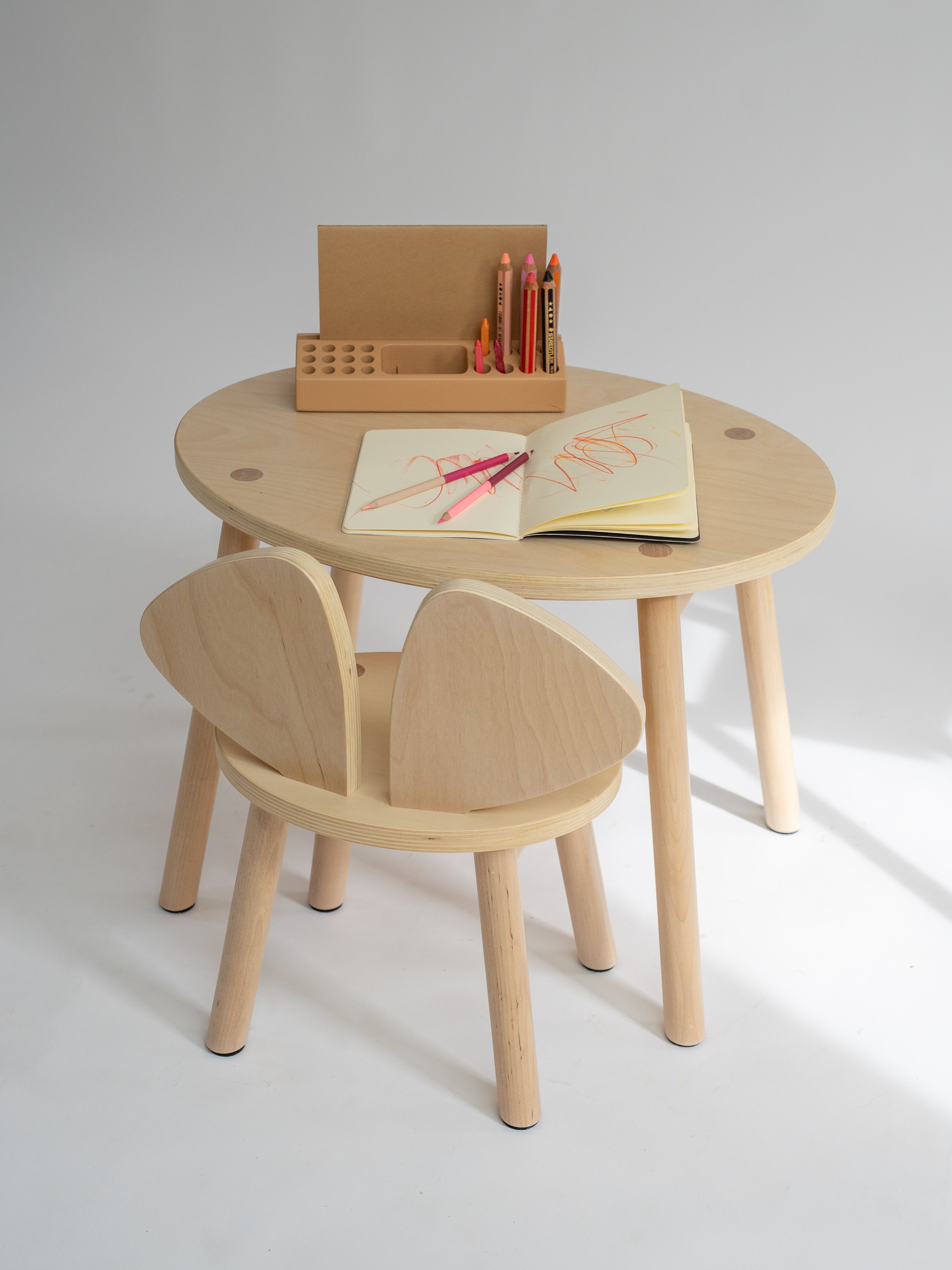 Wooden children's table and chair set with art supplies on a white background