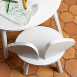 White children's table with leaf-shaped design on a terracotta tiled floor.