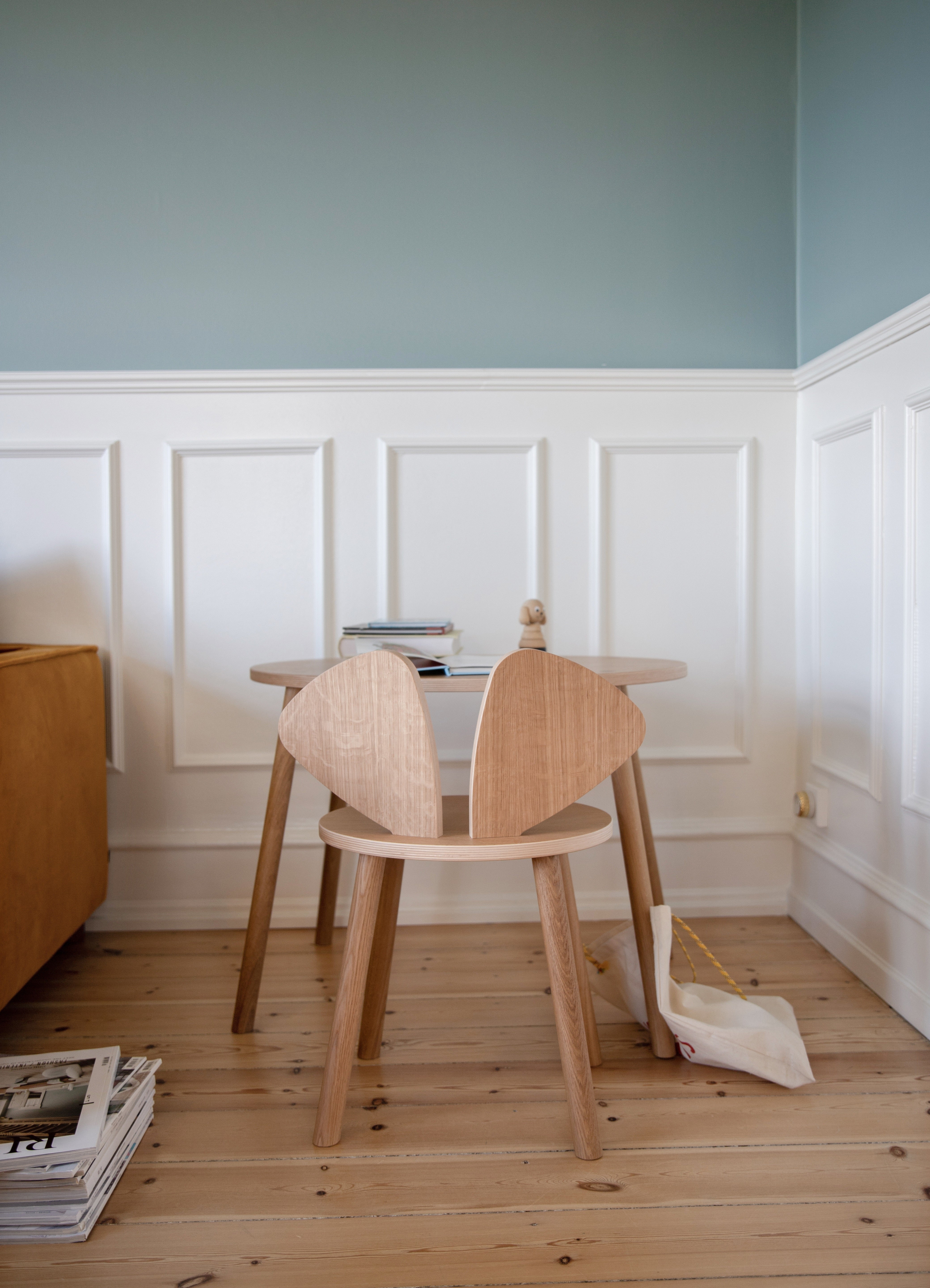 Two wooden chairs in a room with light blue walls and white wainscoting.
