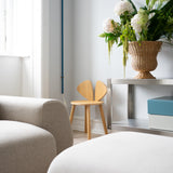 Modern living room with a beige sofa, Mouse Oak Junior chair, and a vase of flowers on a table.