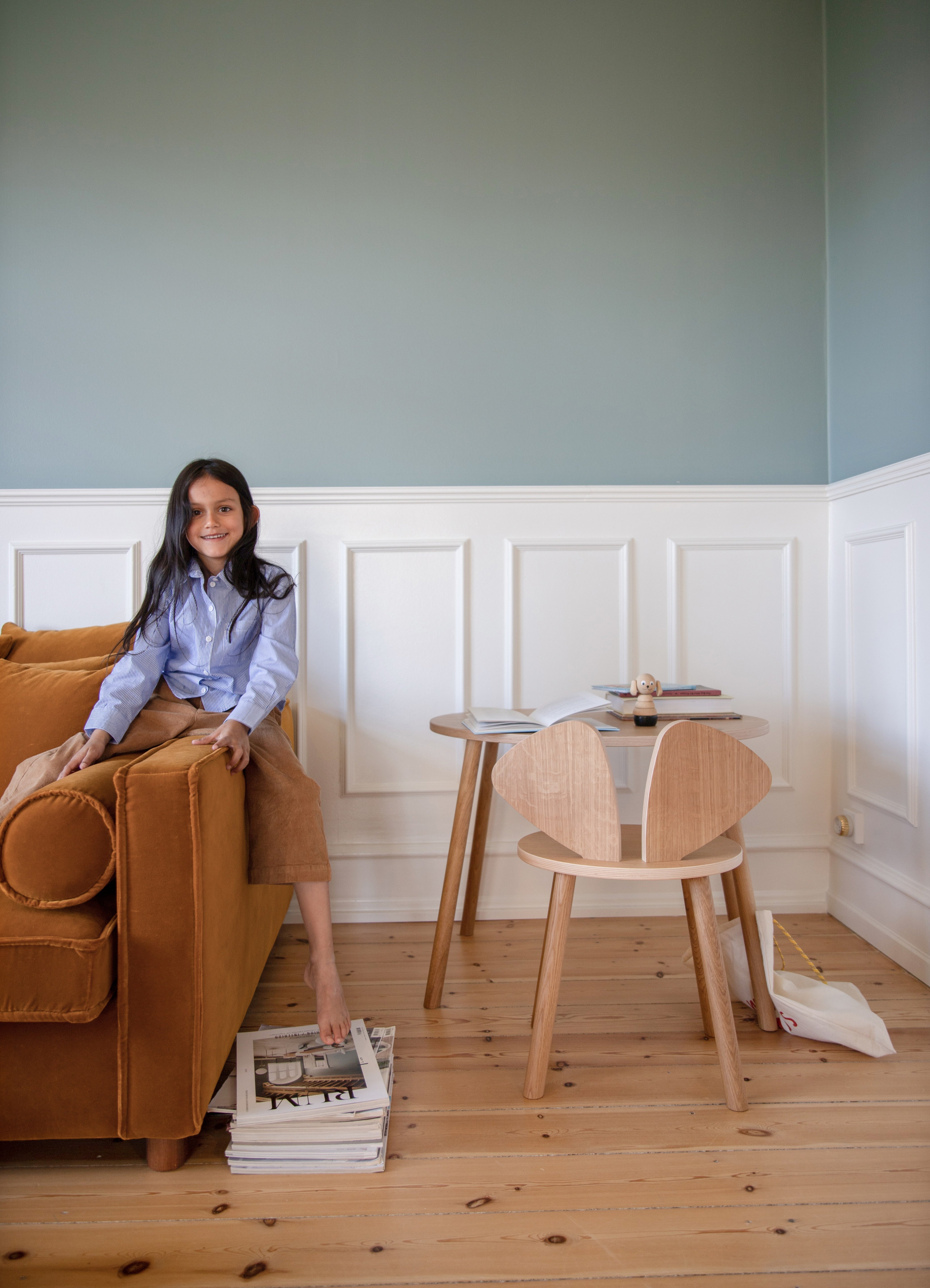 Woman sitting on a brown sofa in a room with wooden flooring and white walls.
