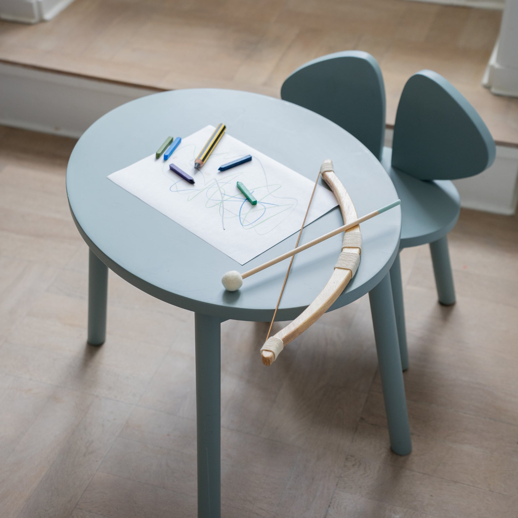 Children's table with drawing materials and chairs in a room.