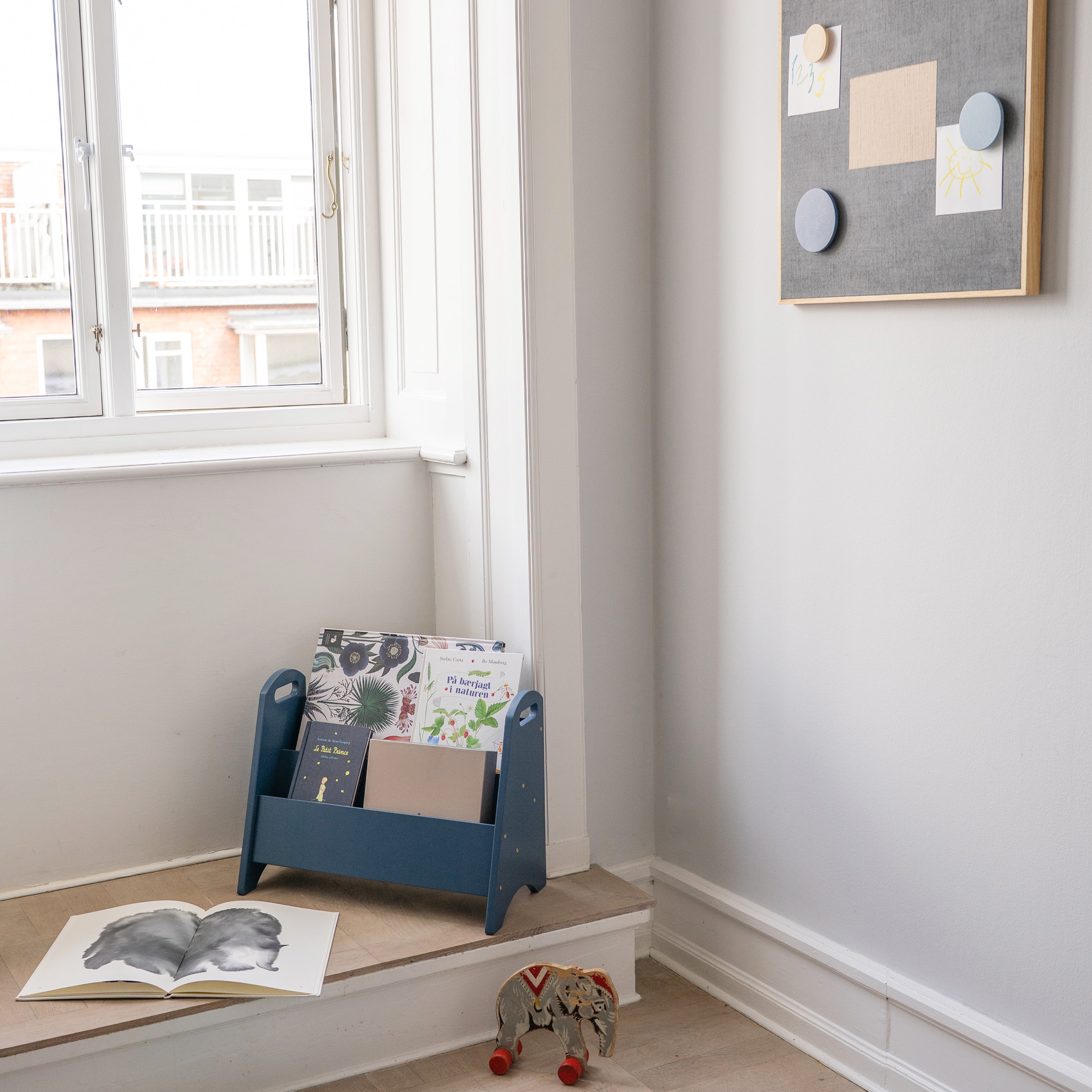 Children's room with a blue bookshelf, books, and toys on a wooden floor.