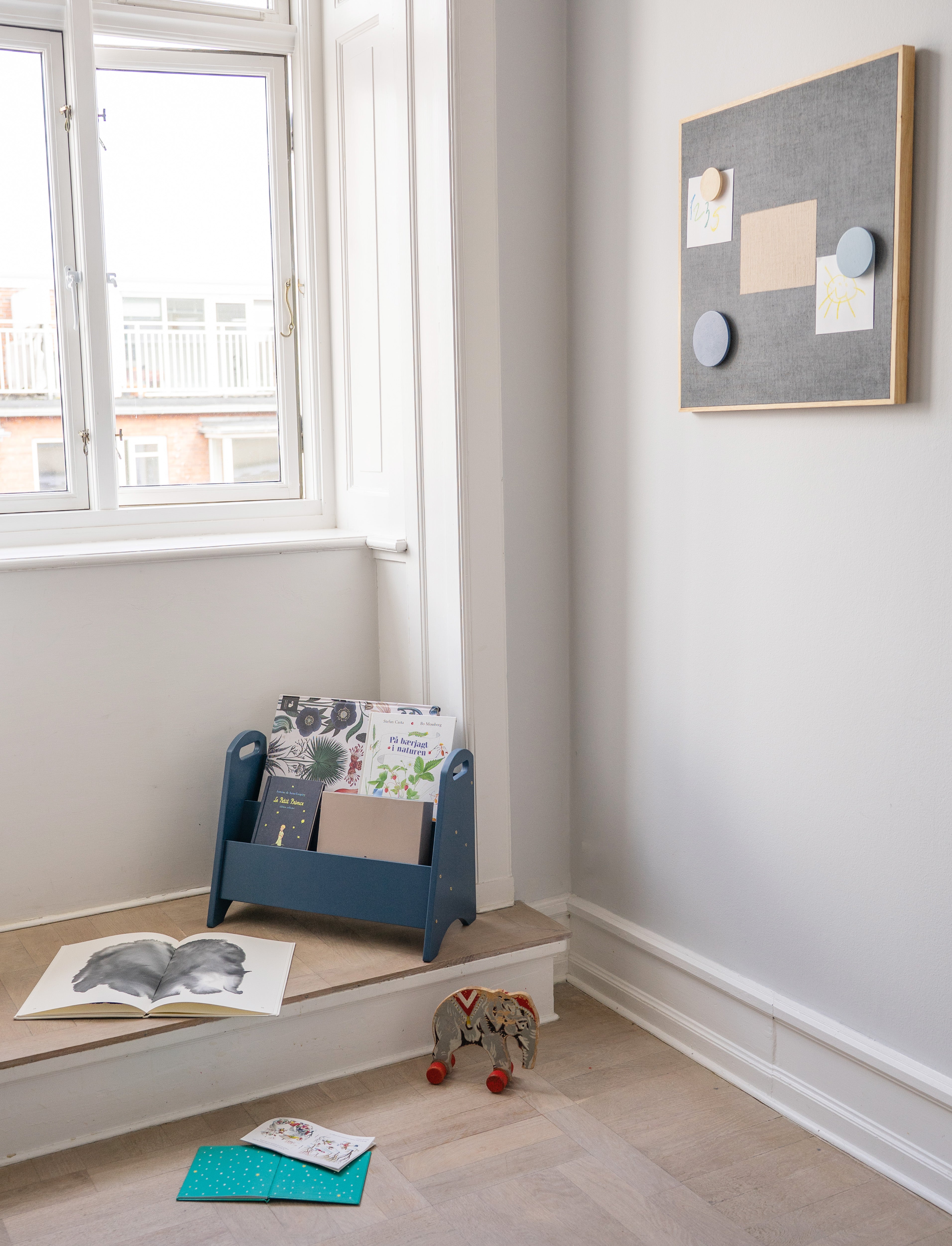 Children's room with a blue bookshelf, books, and toys on a wooden floor.