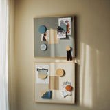 Two decorative boards with shapes and photos on a beige wall