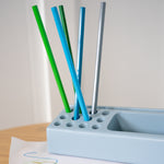 Set of colorful straws in a holder on a light surface