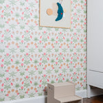 Children's step stool against a floral wallpapered wall with a framed picture.